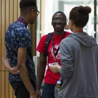 Three students are standing at the entrance to the Main Library and talking.